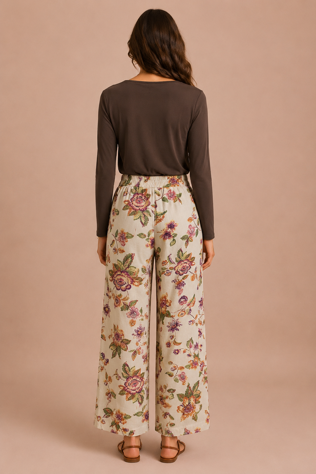 Woman wearing a brown long-sleeve top and floral wide-leg pants on a beige background