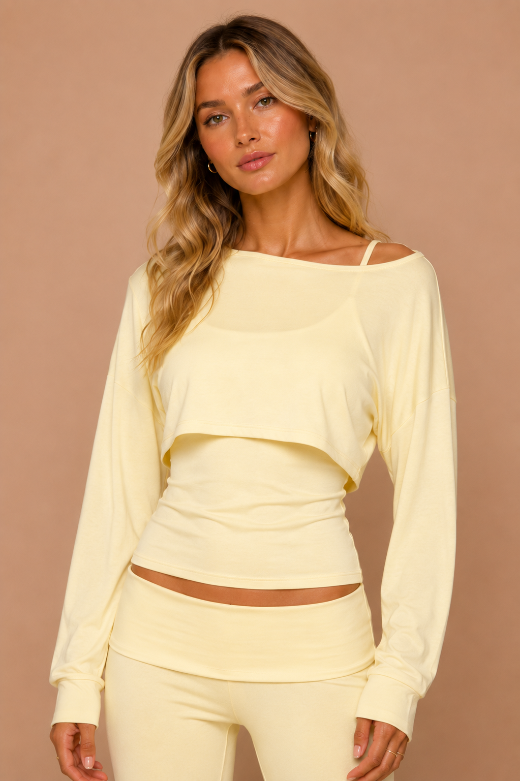 Woman wearing a light yellow long-sleeve top and pants against a beige background