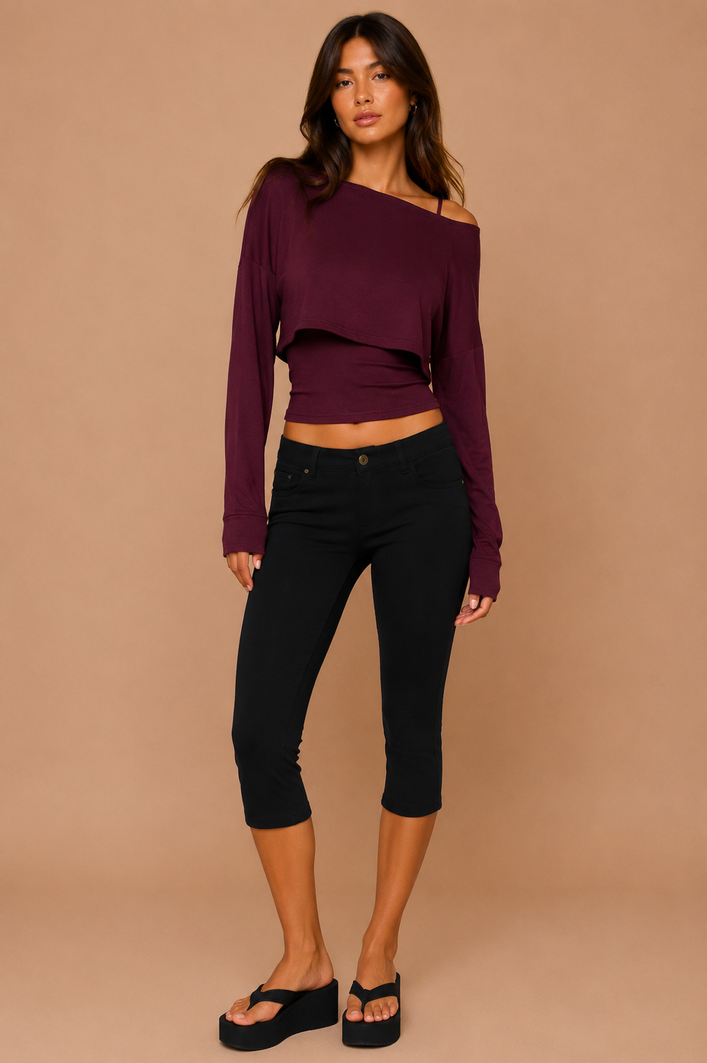 Woman wearing a purple long-sleeve top and black capri pants on a beige background
