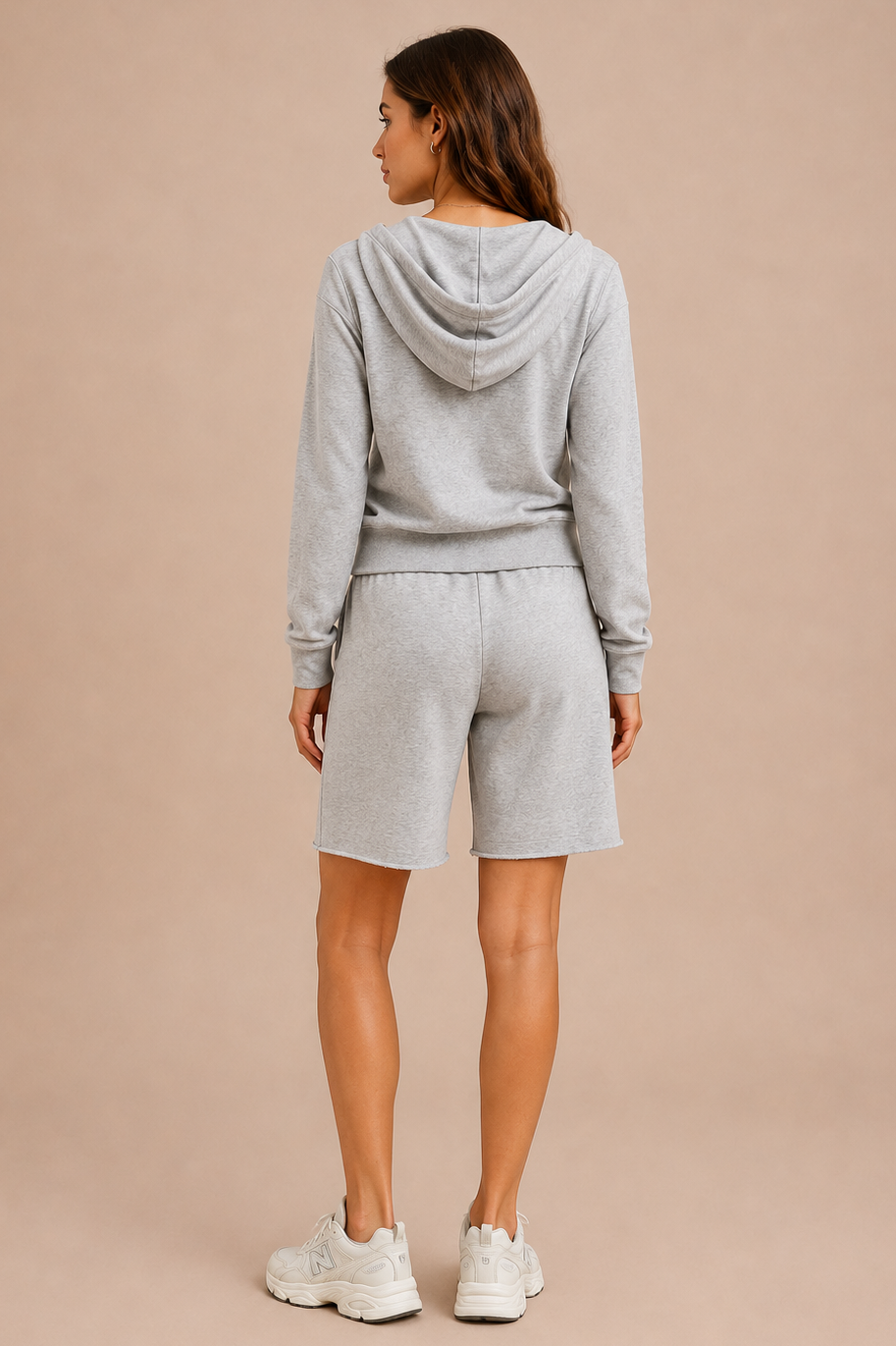 Woman wearing a gray hoodie and shorts set on a beige background
