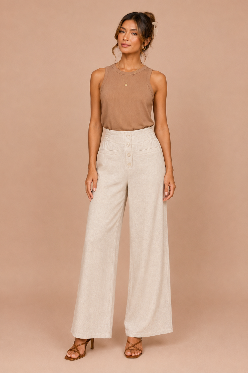 Woman wearing a brown sleeveless top and beige wide-leg pants against a beige background