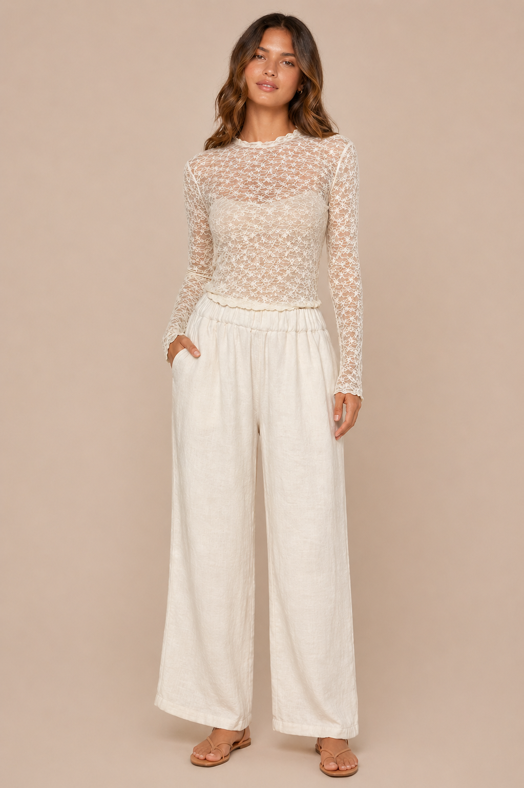 Woman wearing a lace top and wide-leg pants on a beige background