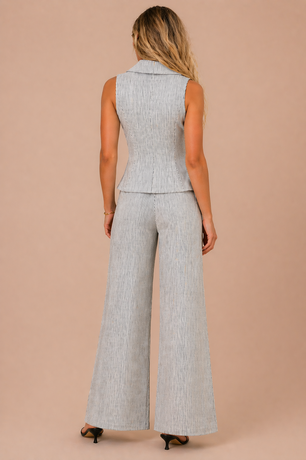 Woman wearing a sleeveless gray top and wide-leg pants on a beige background