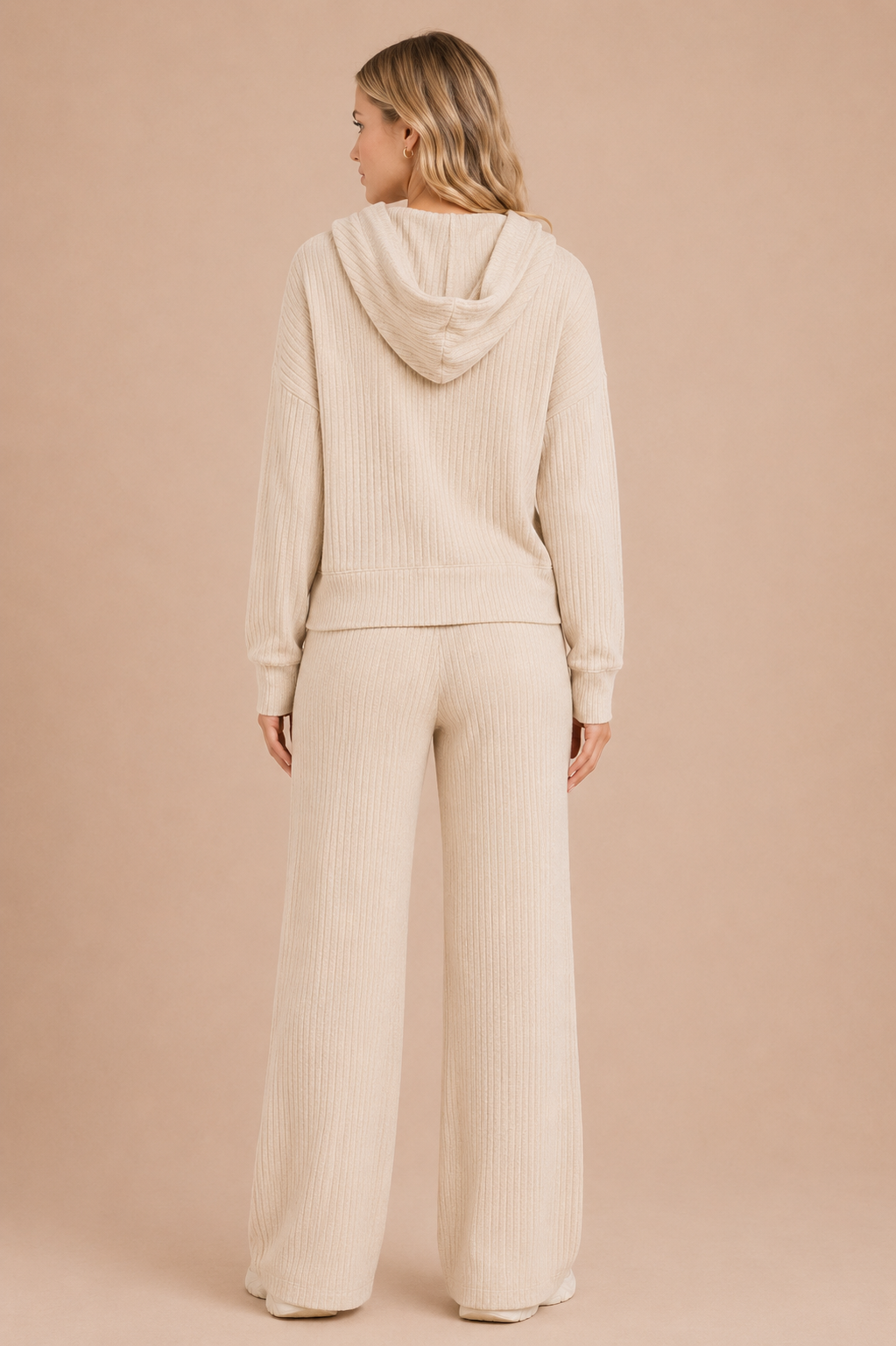 Woman wearing a beige ribbed hoodie and pants on a beige background